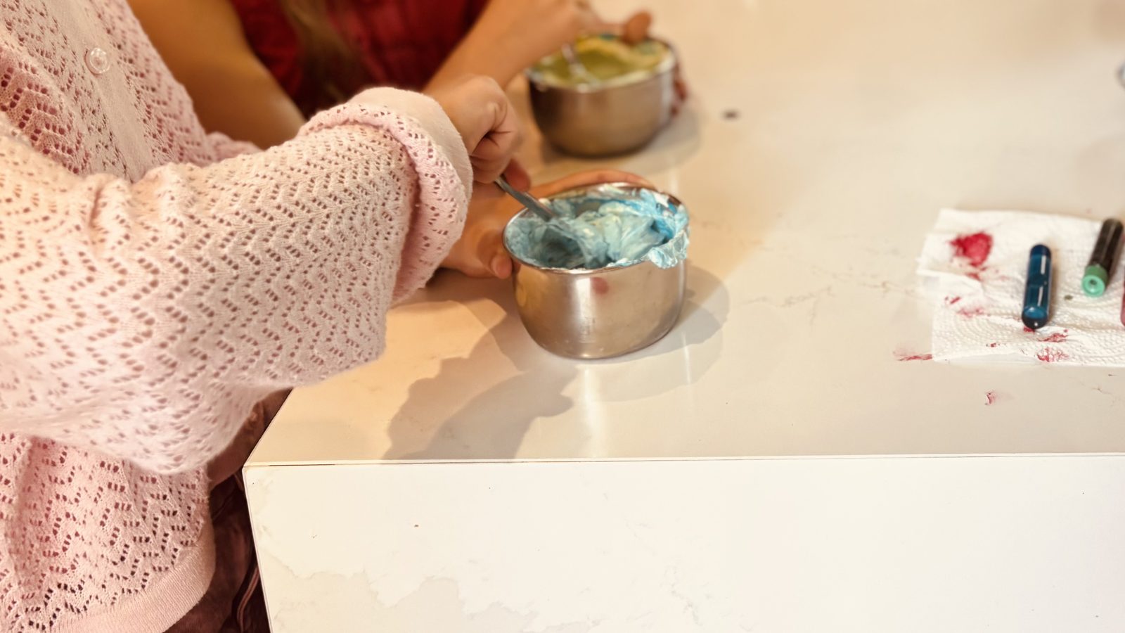 Des mains colorent un bol de chantilly avec un colorant alimentaire