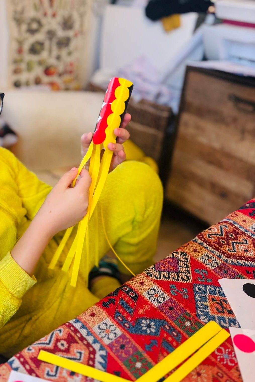 Mains d'enfant tenant un koinobori fini en rouleau de carton couvert d'écailles rouges et jaunes, avec une longue queue en fines bandes de papier jaune qui pend