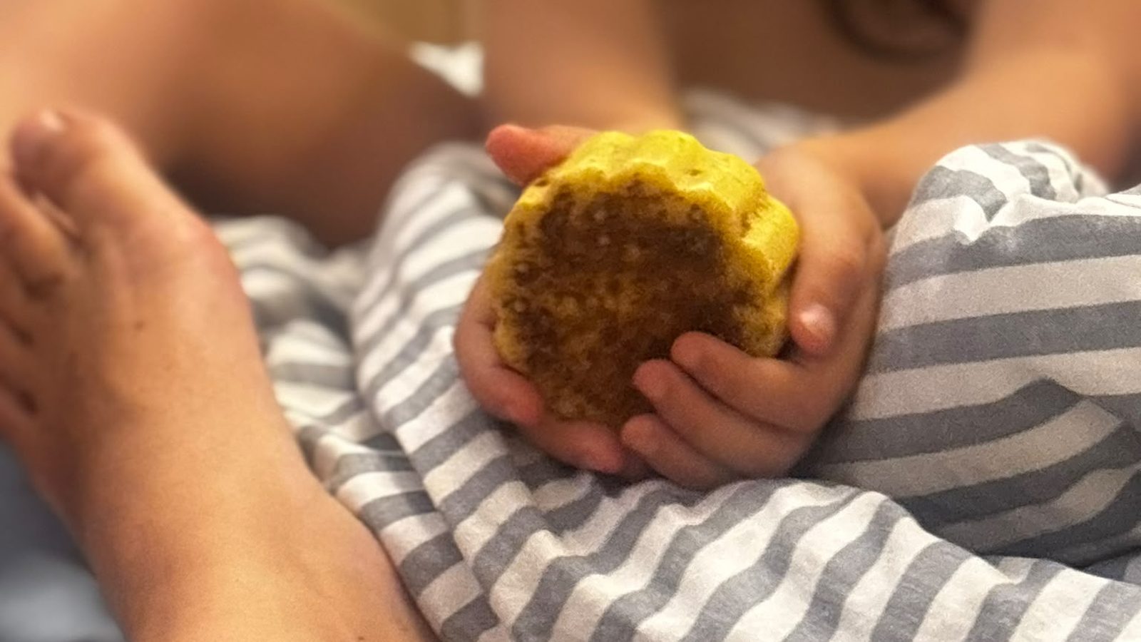 Mains d'enfant tenant une barre de massage à la cannelle, un pied de parent en attente au premier plan