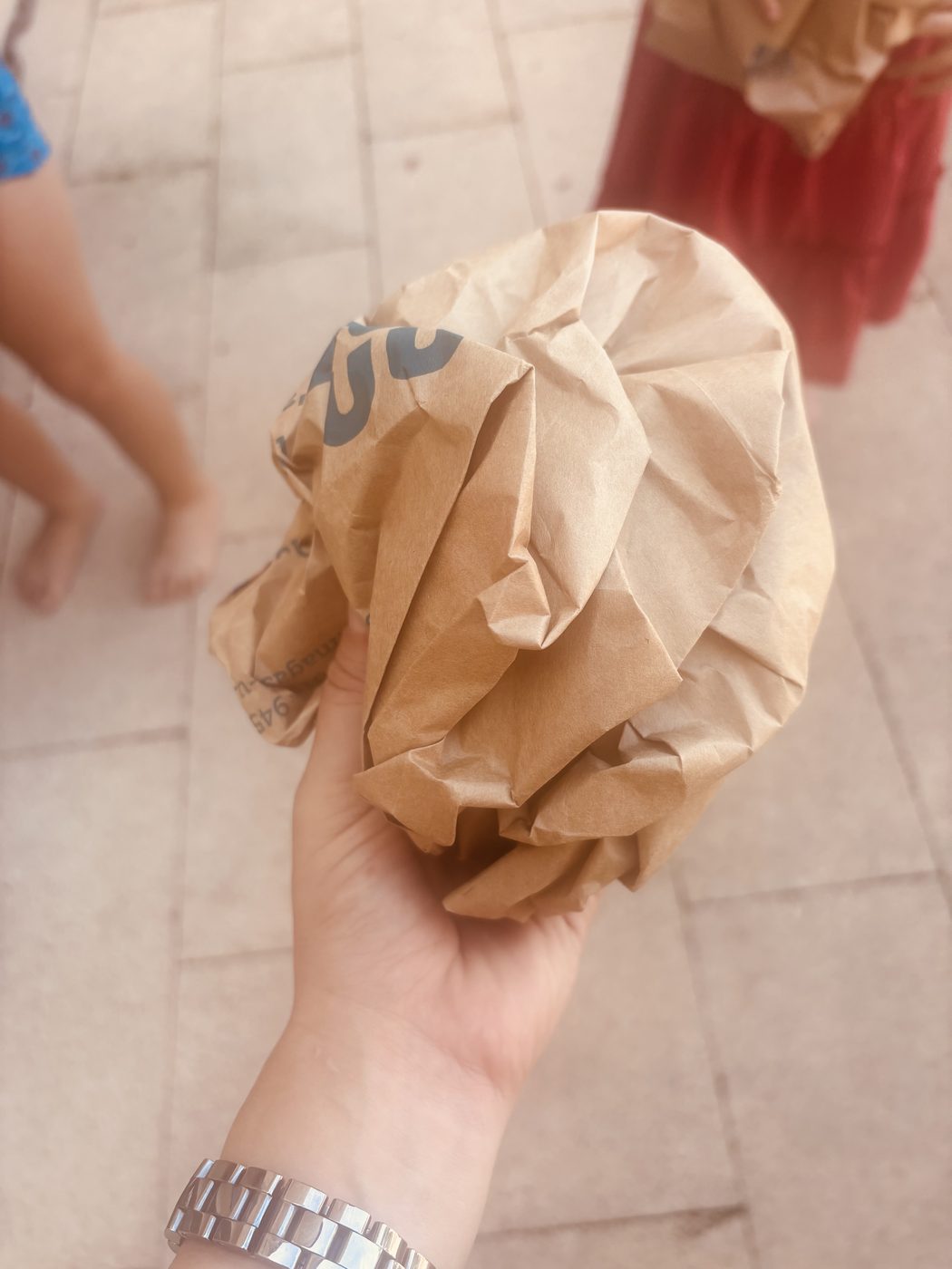 Une main d'adulte tient un sac en papier kraft froissé en une grosse boule serrée