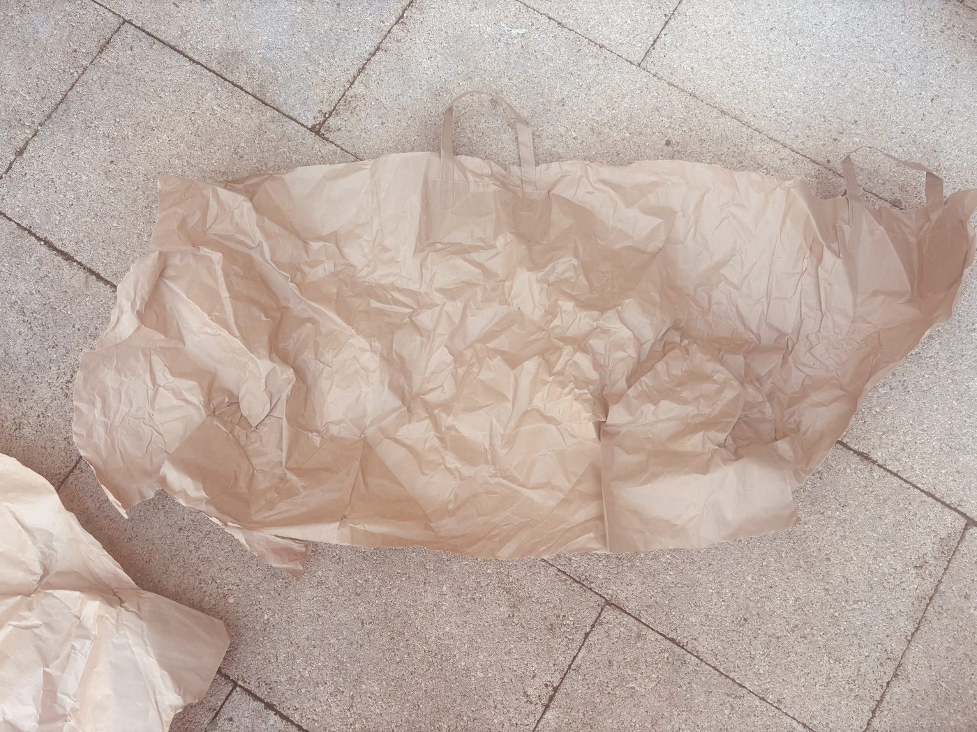 Le sac en papier kraft rouvert à plat sur une terrasse, couvert de plis et de bosses