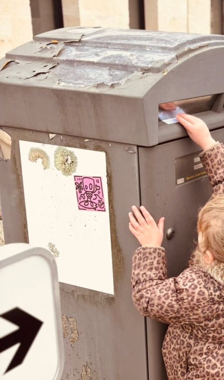 Main d'un enfant glissant une lettre dans la fente d'une boîte aux lettres publique